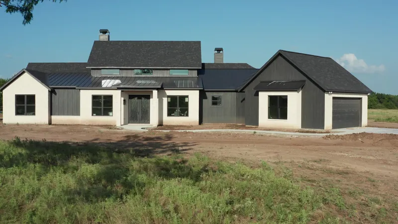 Front elevation of a custom home in white brick and dark board-and-batten with an iron entry door