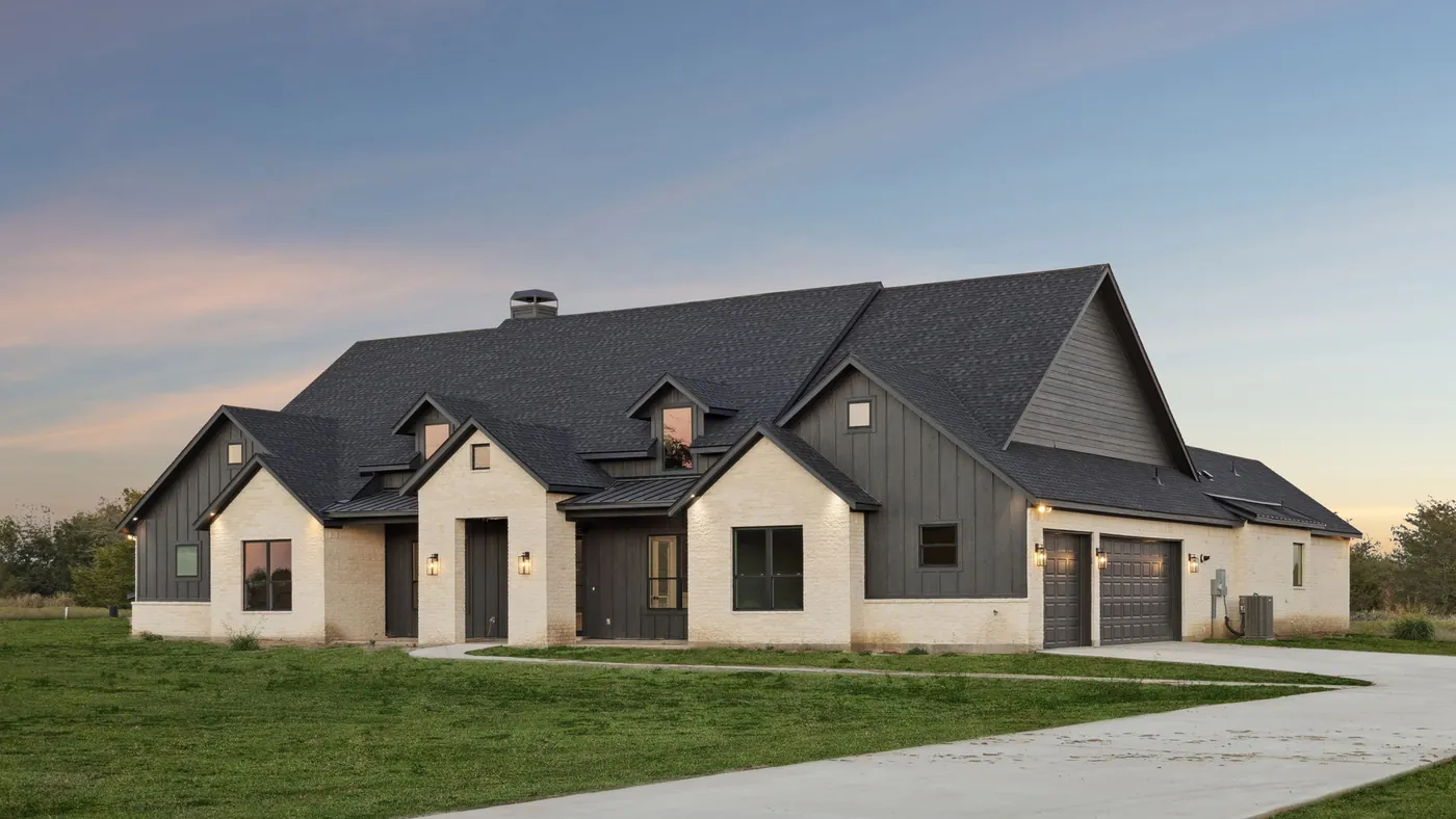 Completed Ark Industries custom home at blue hour with porch lights on