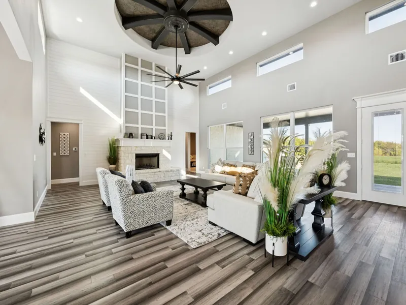 Open living and kitchen with soaring vaulted ceiling and black-framed windows