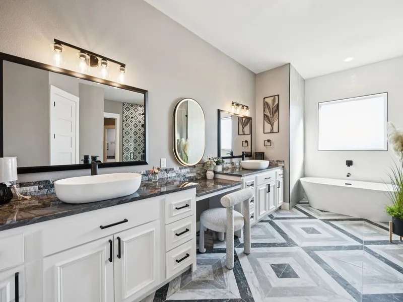 Primary bath with freestanding tub, patterned tile shower, and double vanity