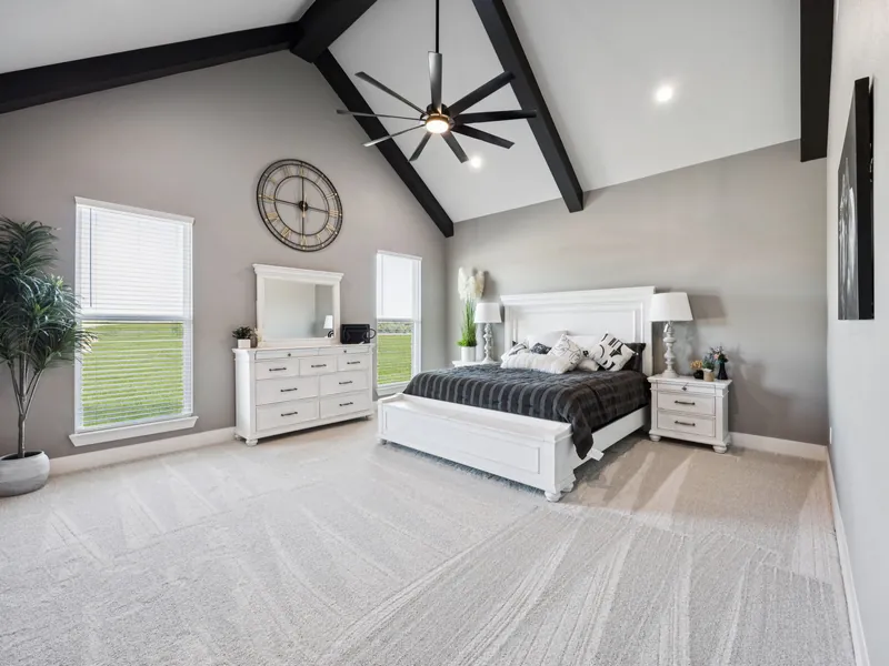 Primary suite with vaulted beamed ceiling, white bed, and views of the pasture