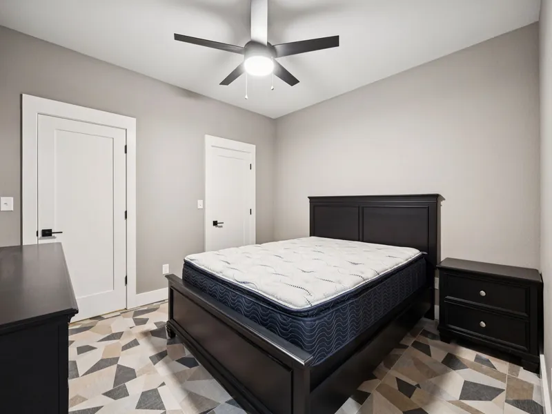 Finished shelter bedroom with real bed, nightstands, and ceiling fan