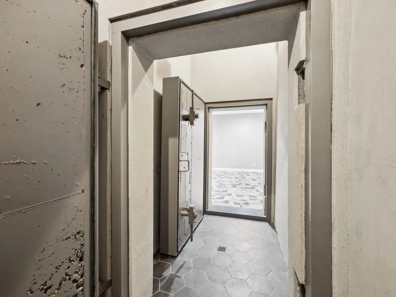 Steel blast door standing open in the poured-concrete entry corridor of an Ark Industries shelter