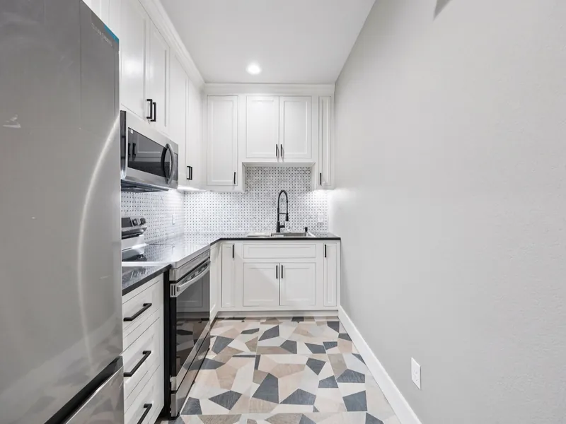 Shelter kitchen with stainless appliances, white cabinetry, and tile backsplash